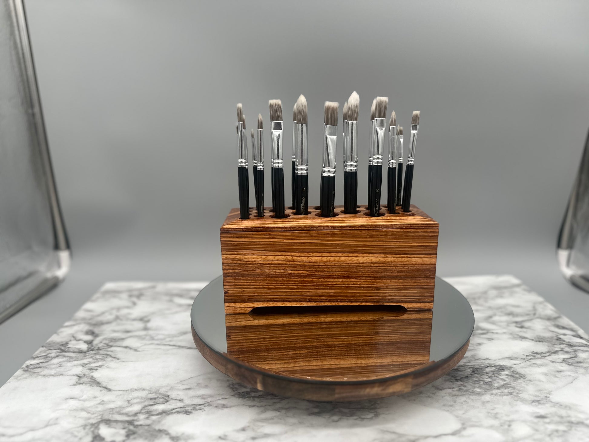Set of paintbrushes in a luxurious Zebrawood wooden holder on a marble surface