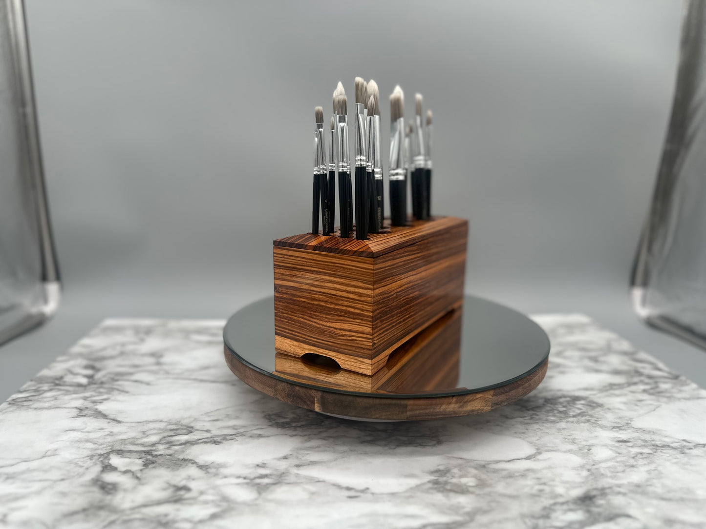 Set of makeup brushes in a wooden holder on a marble surface